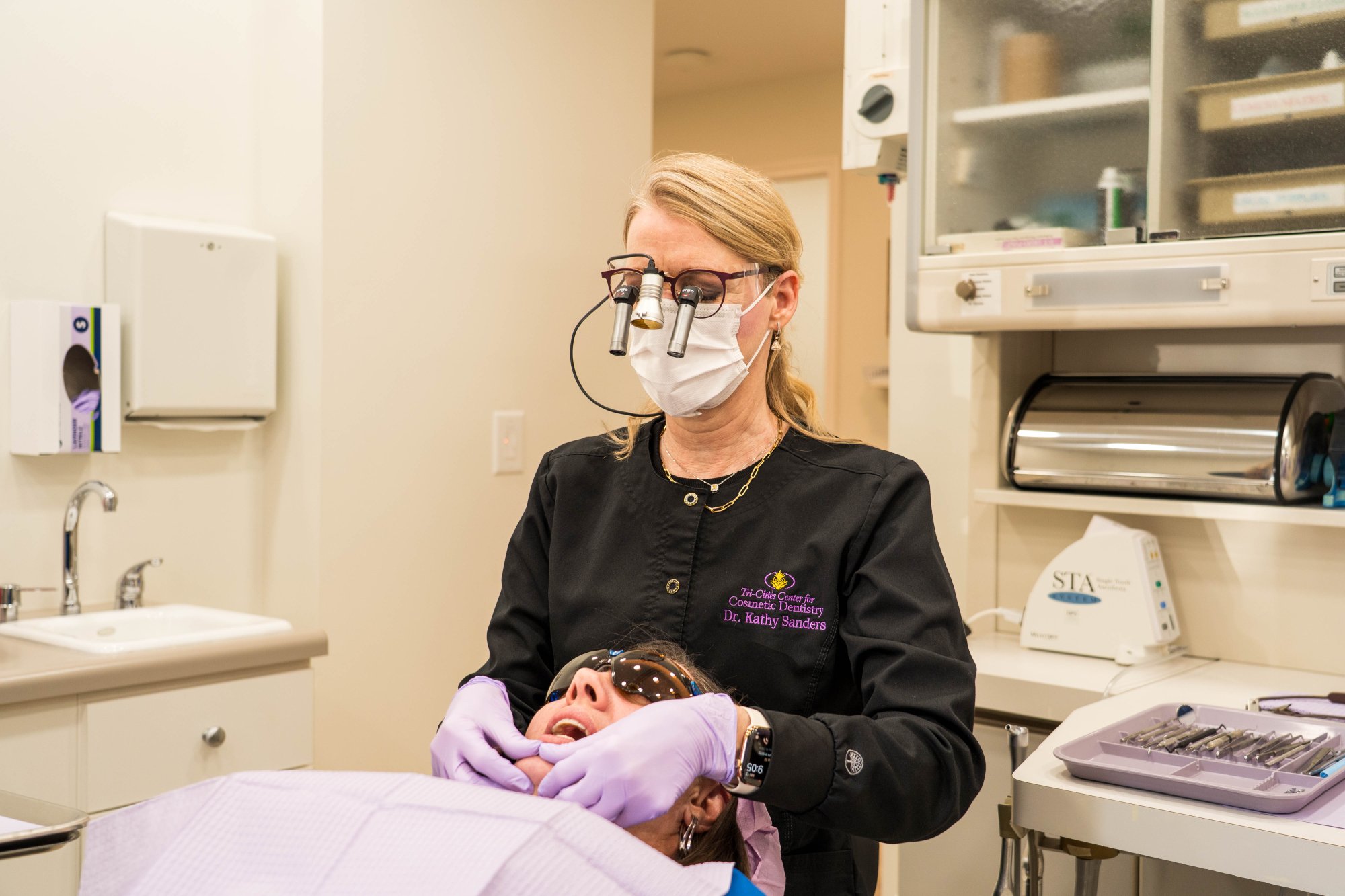 Dr. Kathy Sanders, DMD, FAACD, wearing a mask and magnifying loupes while performing a dental procedure on a patient in a fully equipped dental operatory – Kingsport Dentist
