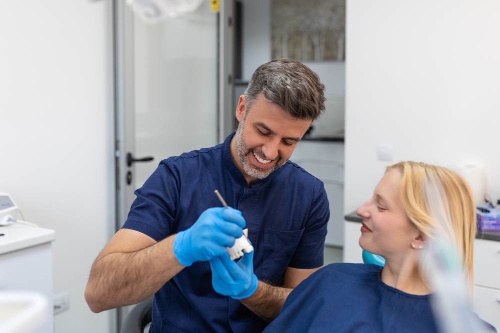 Dentist Explaining Dental Crown Model – Dental Crowns in Kingsport, TN A friendly dentist uses a model to explain the process of dental crowns to a patient, highlighting personalized care and advanced restorative dentistry in Kingsport, TN.