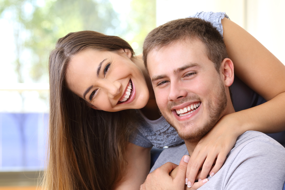 Couple Smiling with Healthy Teeth - Comprehensive Dental Hygiene Program A cheerful couple with bright smiles embraces, reflecting the benefits of consistent oral hygiene and professional preventive care – Comprehensive Dental Hygiene Program.
