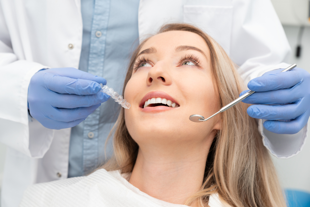 Clear Aligner Consultation - Complex Comprehensive Dentistry A female patient smiles while a dentist demonstrates a clear aligner treatment, symbolizing advanced orthodontic and restorative dental care – Complex Comprehensive Dentistry.