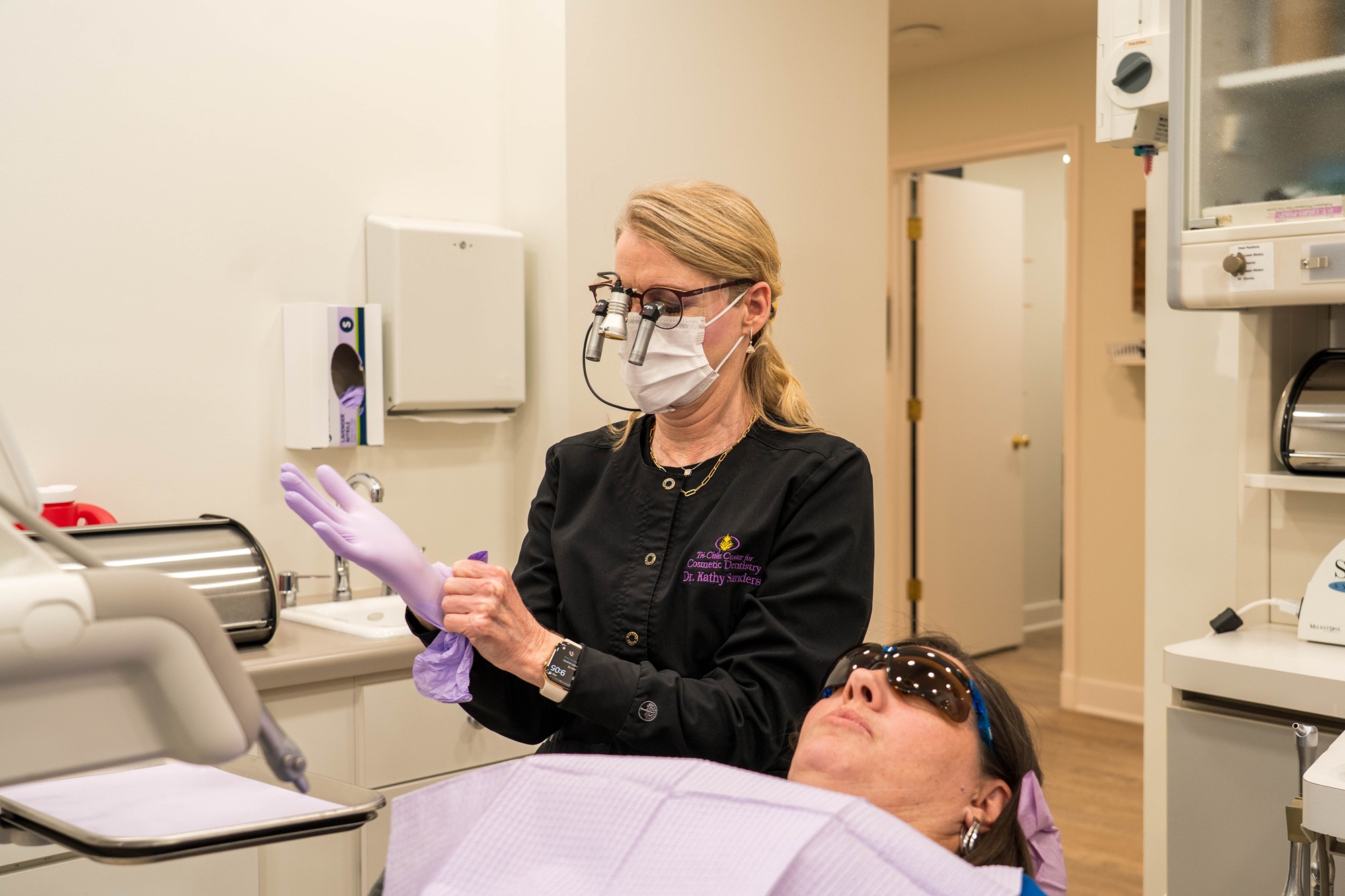 Dentist Preparing for Implant Procedure - Implant-Supported Dentures A dentist puts on gloves before starting a treatment, ensuring a clean, safe, and professional environment for patients receiving implant-supported dentures.